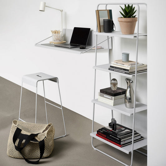 Modern office setup with a white shelf, desk, and stool on a light gray floor.